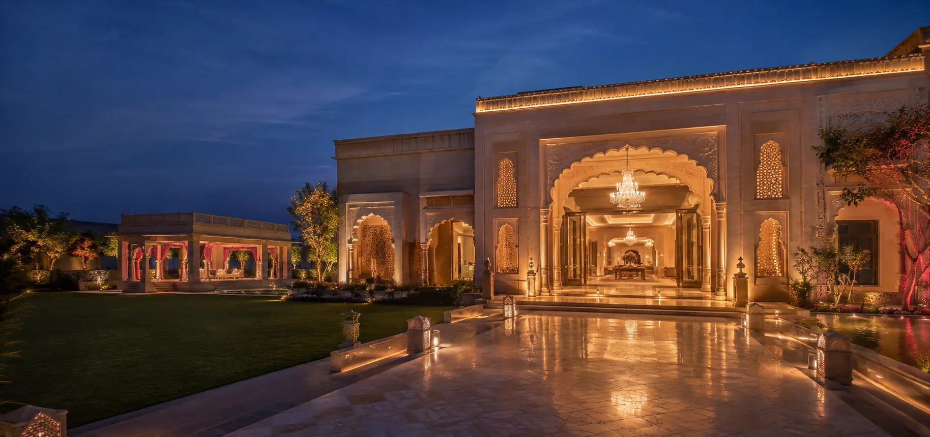 Grand Indian event property at blue hour showing its entrance, lawn, pavilion and illuminated interior